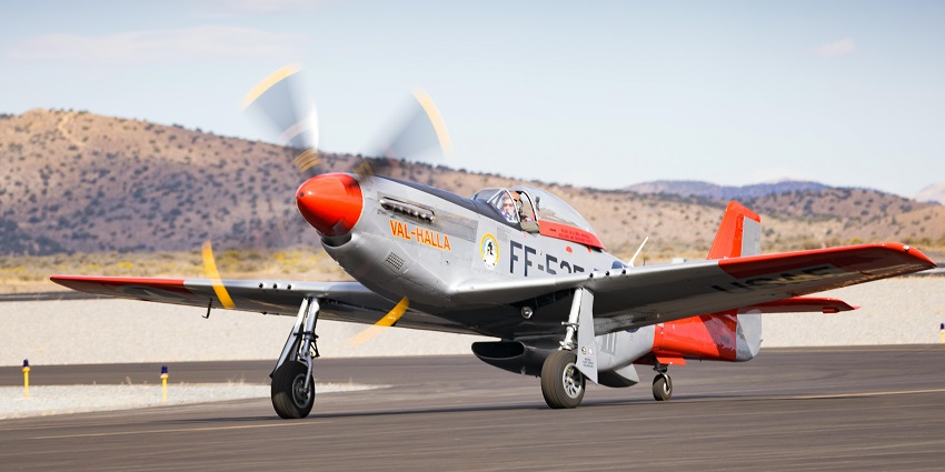 Small propeller aircraft on the runway of an airport with multiple signs on its body