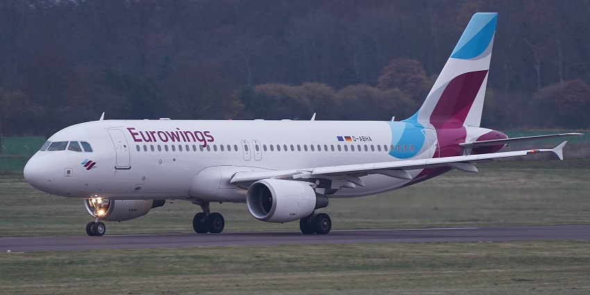 Airbus A320 commercial aeroplane on the runway of an airport with green plains in the back
