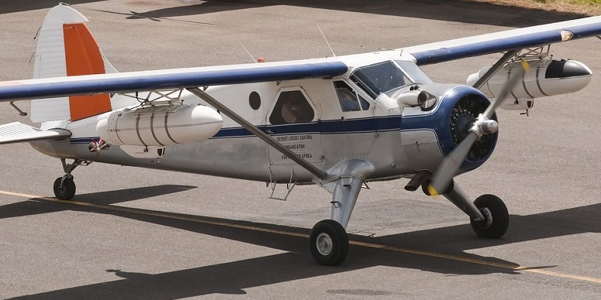 Small propeller aircraft on the runway of an airport with blue and orange stripes