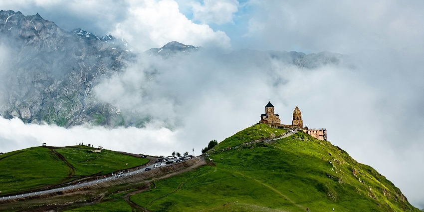 Image of a Church on a mountain in Georgia with picturesque view of lush green mountains
