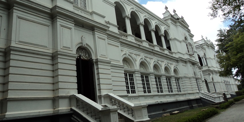 An image of a grand neoclassical building with ornate arches and dual staircases