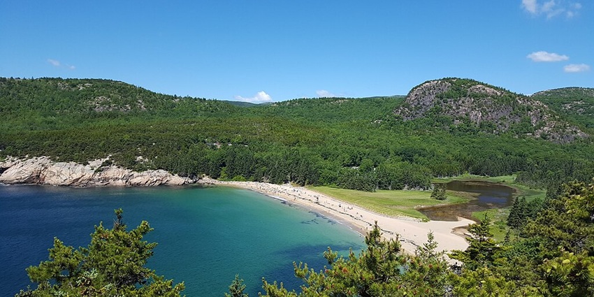 A view of the rocky shore at one of the top national parks in the US with forested hills.
