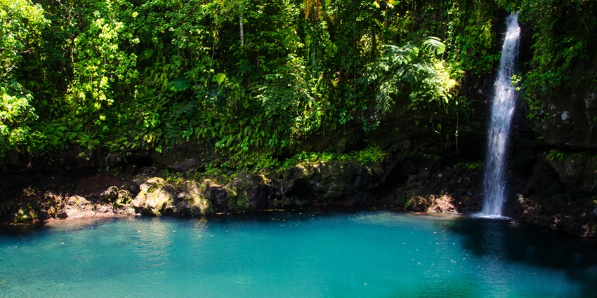 A serene view of a beautifully cascading waterfalls on the Samoa Islands surrounded by greenery