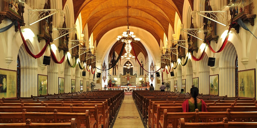 An image of a church congregation attending a service with floral decorations and chandeliers inside the church, during Agera.