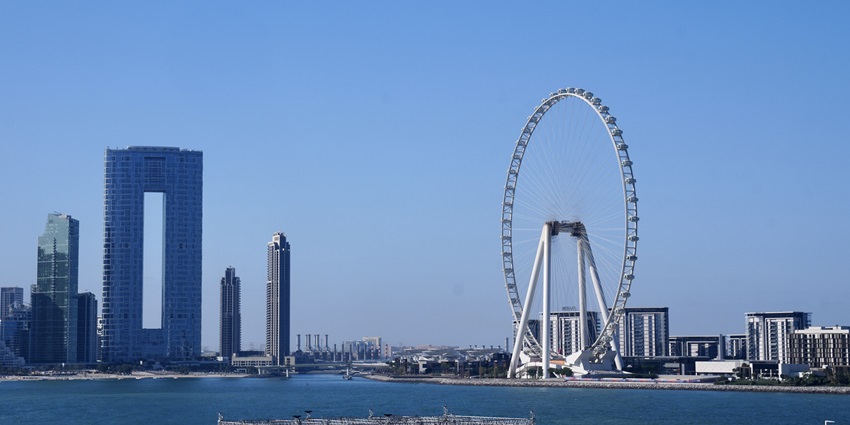 A distant view of a massive ferris wheel in Dubai with a water body visible in front