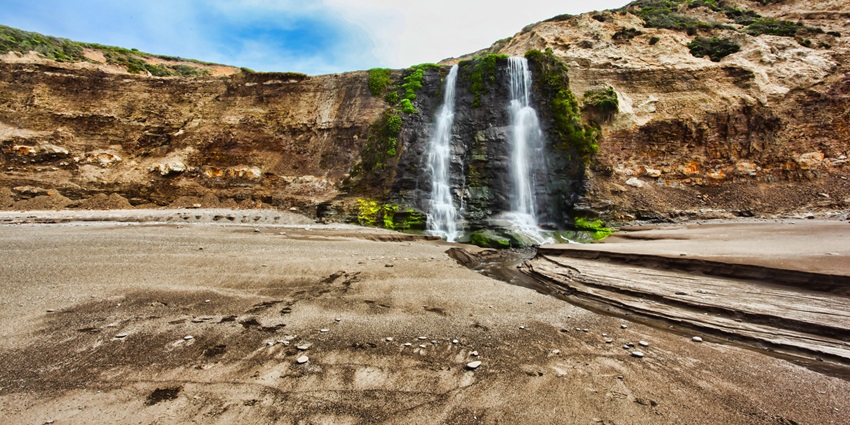A rare tidefall cascading directly into the Pacific Ocean along California’s rugged coastline.