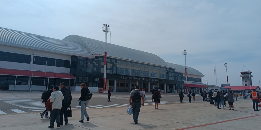 Passengers are walking towards the Alcantarí airport terminal while carrying their luggage.