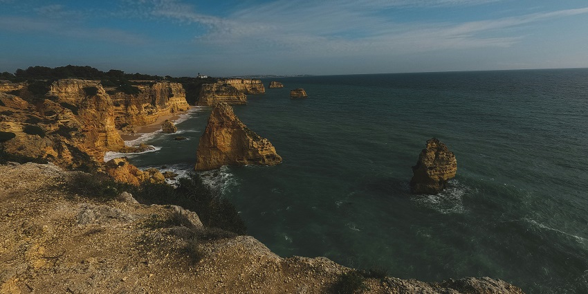 The beautiful Algarve Coastline featuring lofty cliffs and deep blue sea water rushing
