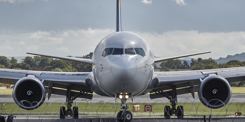 An aircraft is taxiing on the runway toward the terminal during partly cloudy weather.