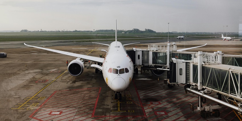 Aeroplane connected to the passenger boarding bridge with runway in the background