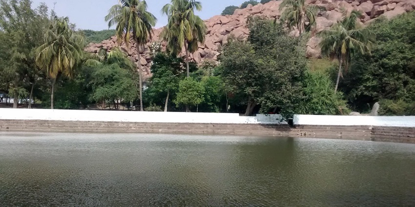 The serene view of the lake reflects the blue sky and the surrounding rocky landscape.