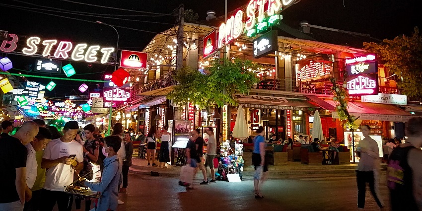 A nighttime view of the bustling Angkor Night Market Street decked with neon lights.