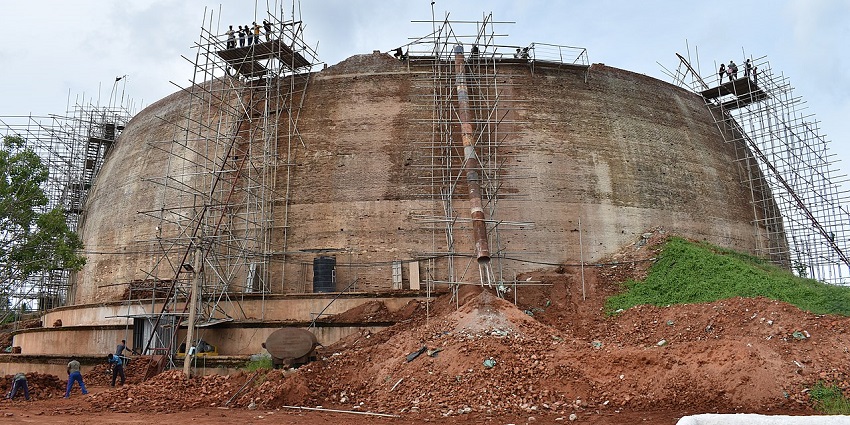 Workers restoring an ancient stupa in Mihintale, surrounded by scaffolding and tools.