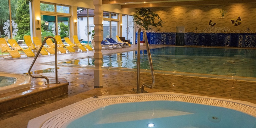 Pool area with a swimming pool, different tubs and benches on the side inside a resort