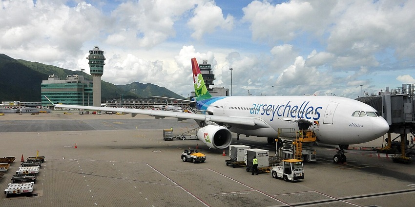An airplane parked near the terminal in Arba Minch Airport in Ethiopia with people unloading the cargo and small trollys