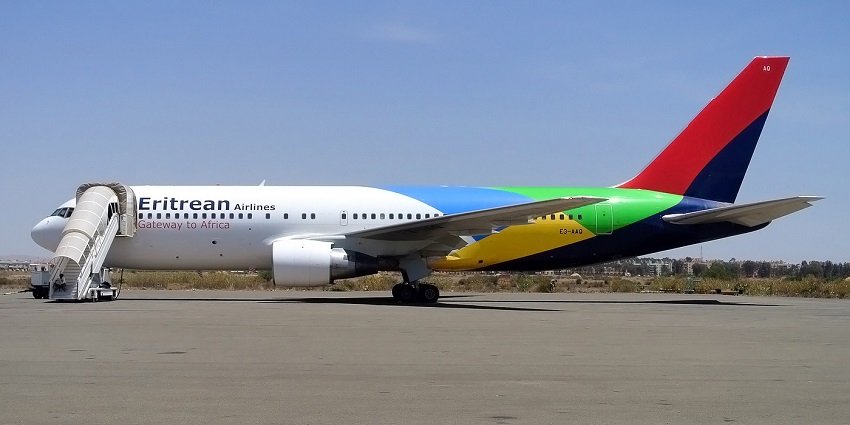 Eritrean Airlines aeroplane with its flag on the tail parked and a man sitting on its stairs