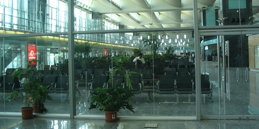 Waiting area inside an international airport with a man behind the glass doors and chairs