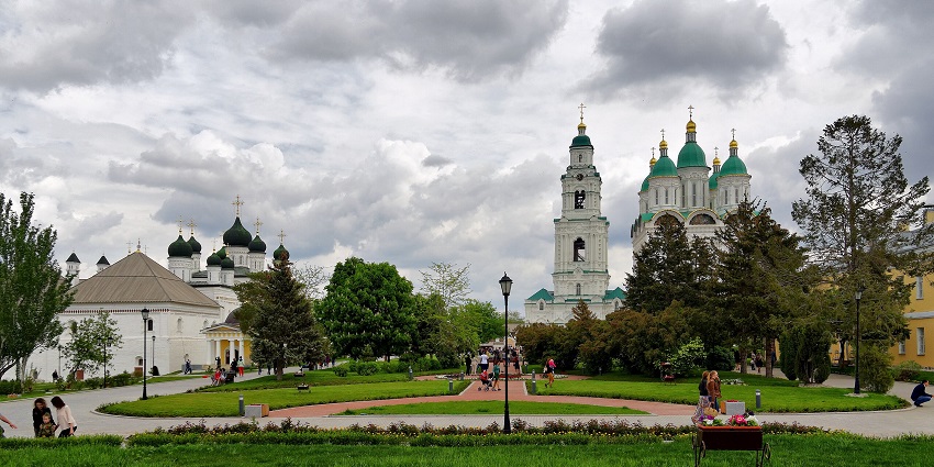 A scenic park with historic churches, green domes, golden crosses, and visitors strolling.