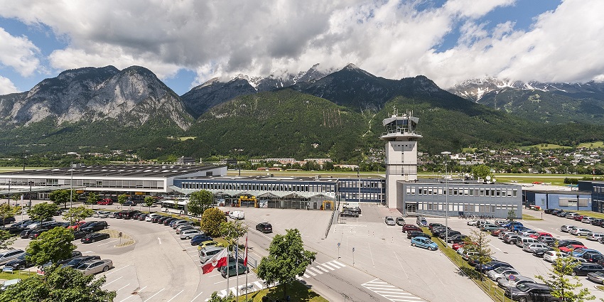 An aerial view of a picturesque airport shows an ATC Tower near the airport's parking area.