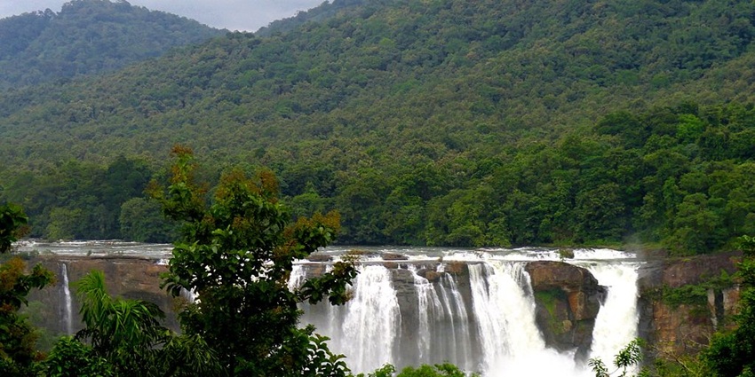 A breathtaking view of Athirappilly Waterfalls cascading down rocky cliffs.