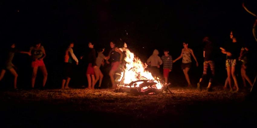 Group of friends gathered around a bonfire, sharing warmth under the night sky