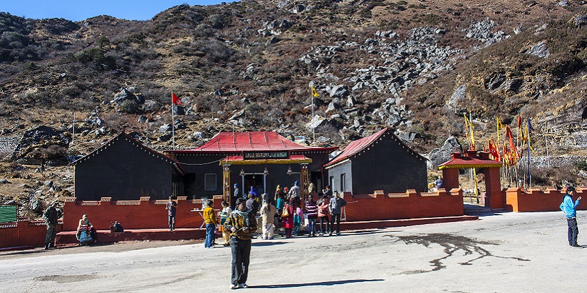 Baba Harbhajan Singh temple with red architecture and multiple flags and people