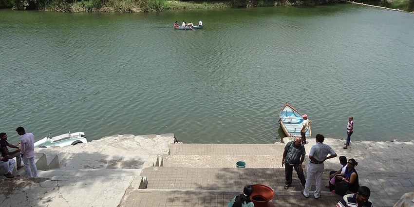 Lake with stairs towards the lakes, people standing, parked boats and people in the boat