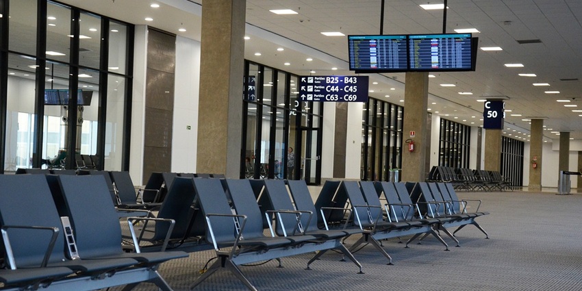 An empty lounge area with steel chairs inside of an airport surrounded by pillars