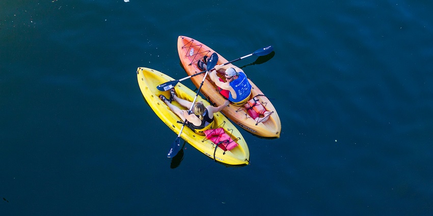 An Image of people on a yellow and orange banana boat being pulled by a motorboat.