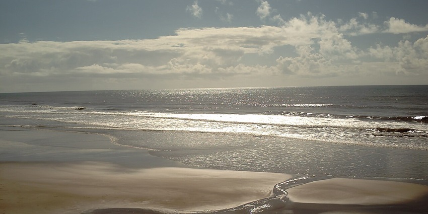 Barra Beach with calm waves and bright reflections of the sun rays hitting its water