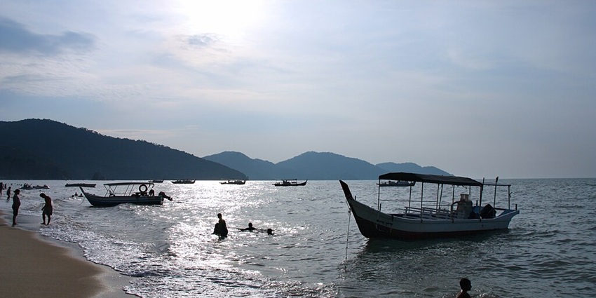 Scenic view of Batu Ferringhi Beach in Penang with sun shining and people swimming