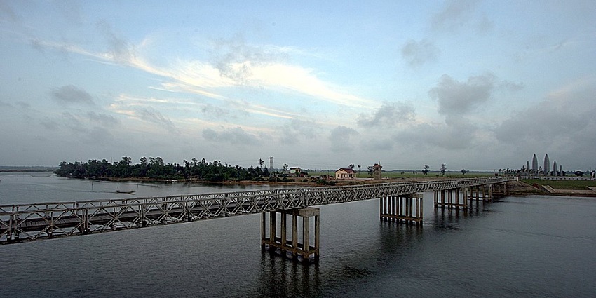 An image of the Ben Hai River in Vietnam, with calm waters and a historic bridge in the background