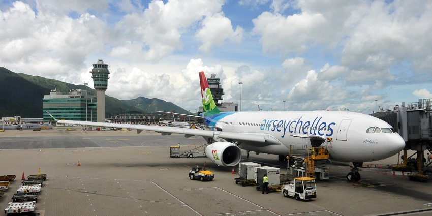 The flight of Air Seychelles is standing on the runway of the airport surrounded by mountains