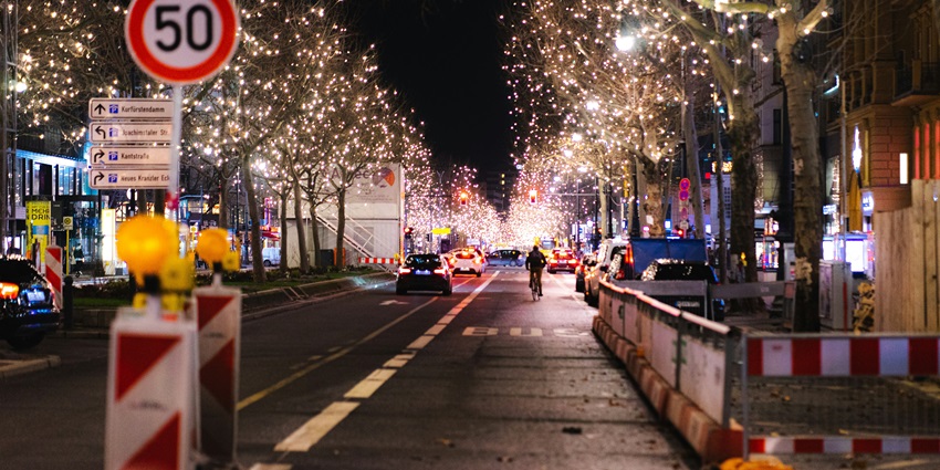 A view of a street in Berlin, Germany decked with trees that are adorned with lights.