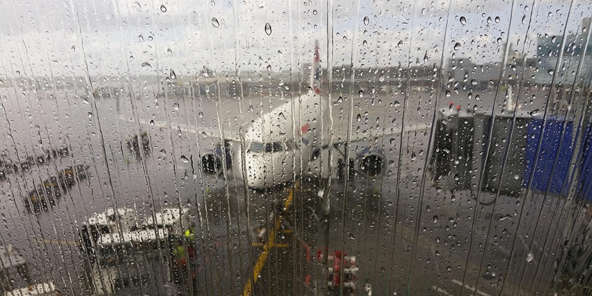 Picture of an aeroplane standing through a wet glass with water dripping on a rainy day