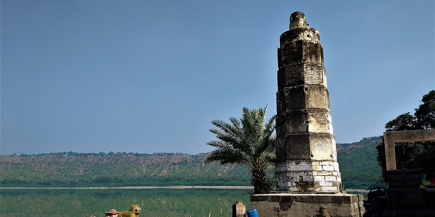 Lonar crater lake with a temple structure near the waterbody and small statues on the complex