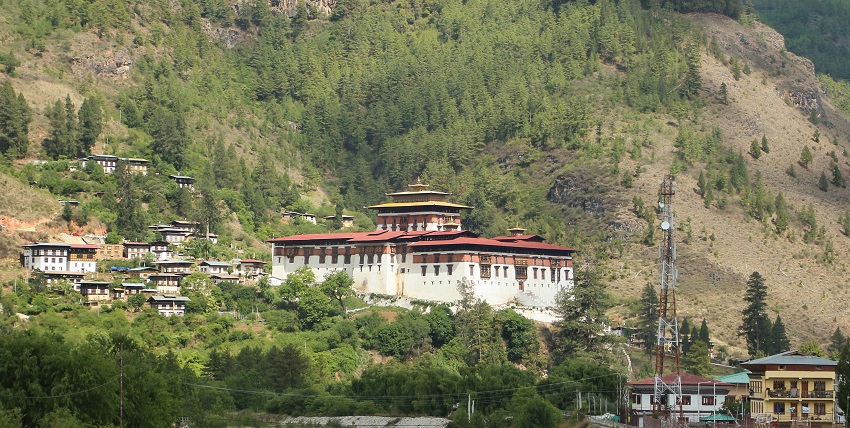 A scenic view of Rinpung Dzong surrounded by lush greenery and clear blue skies, capturing the best weather for visitors.