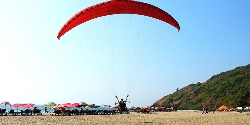 An image of a parachute in Arambol Beach with gentle waves, and a long shoreline.