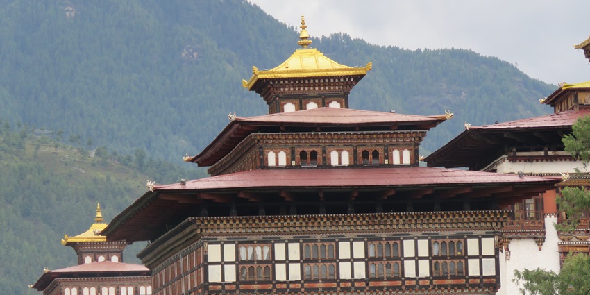 A stunning view of Tashichho Dzong Bhutan under a clear blue sky, surrounded by greenery, making it a perfect time for sightseeing.