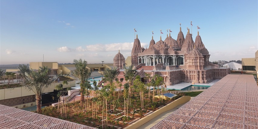Magnificent pink sandstone temple with intricate carvings, surrounded by gardens.