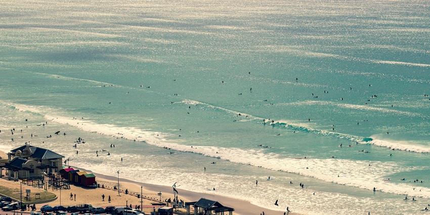 A sunny day at the beach in Cape Town, with clear blue skies and gentle waves.