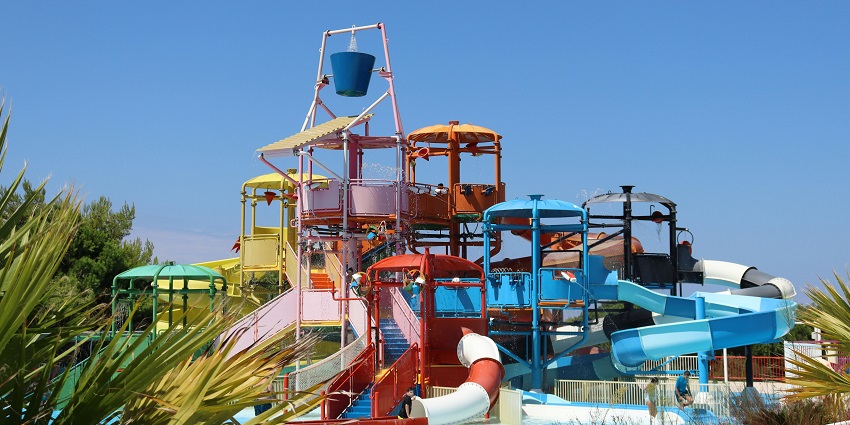A water park structure with slides and a large tipping bucket under a clear blue sky