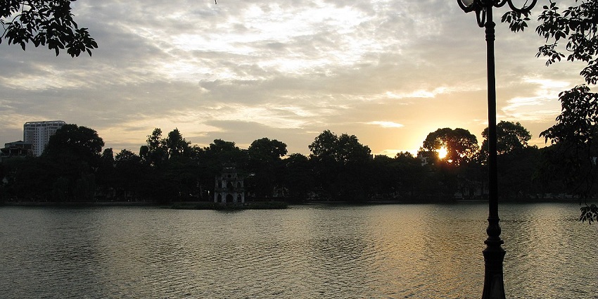 A beautiful sunset over Hoàn Kiếm Lake, creating a tranquil atmosphere