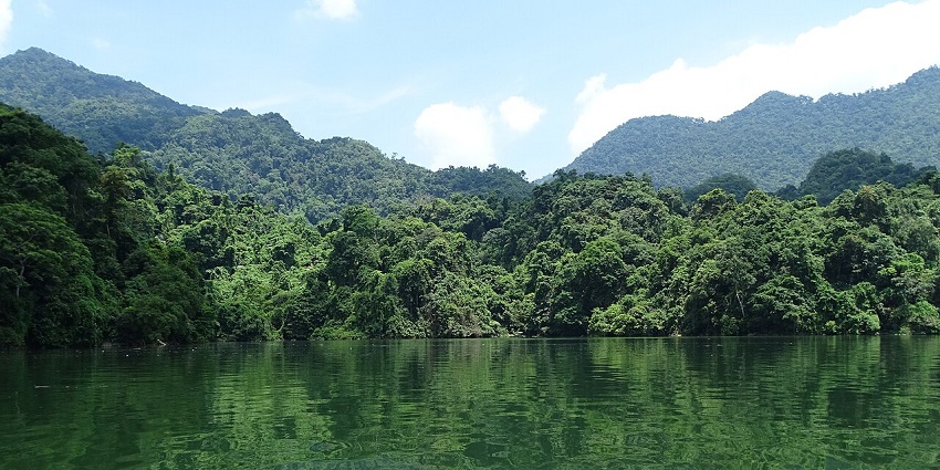 Ba Be Lake under a clear blue sky, reflecting the surrounding mountains