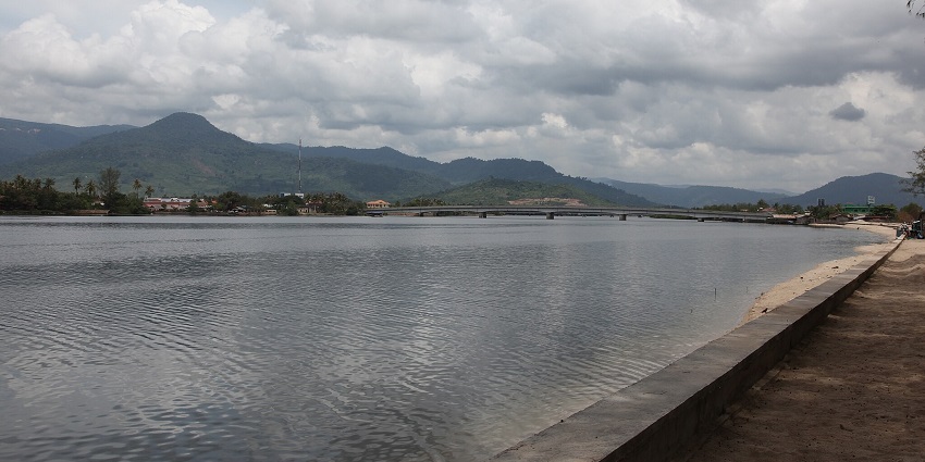 image of River Teuk Chhou near the old Kampot town bridge with water and structures.