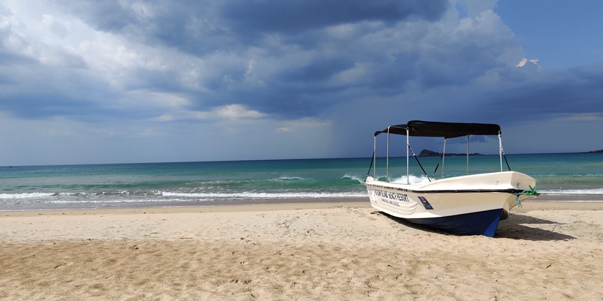An image showing Pathirakali Amman Theertham in Trincomalee, with a scene of a boat.