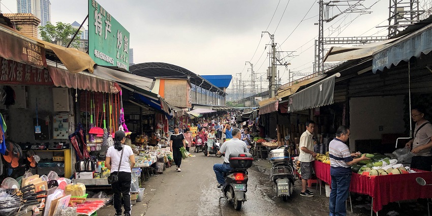 A picture of Maeklong Railway Market in the early morning, bustling with vendors and tourists.