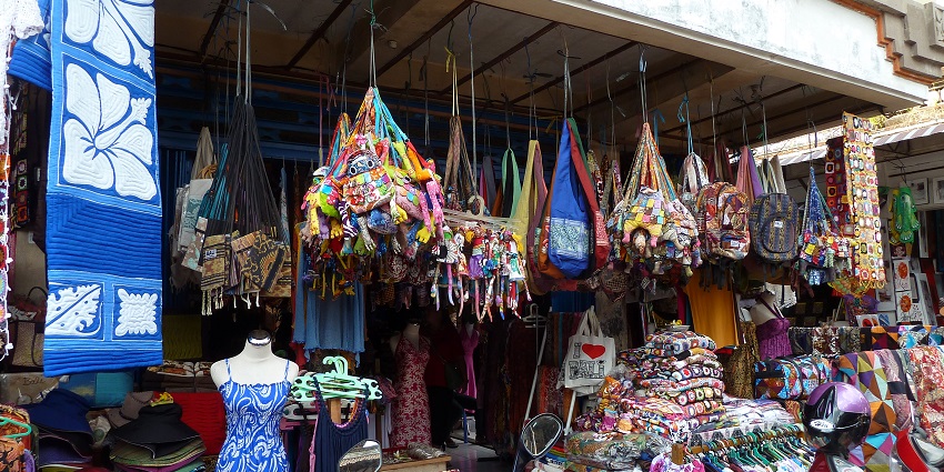 A colorful scene of Badung Market filled with traders and customers under a bright blue sky.