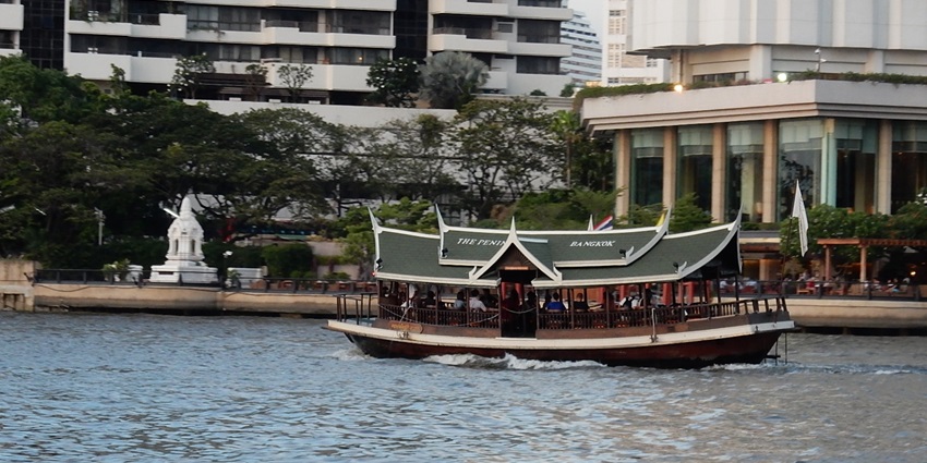 View of the Chao Phraya River Cruise with lit temples and city lights reflecting on the river.