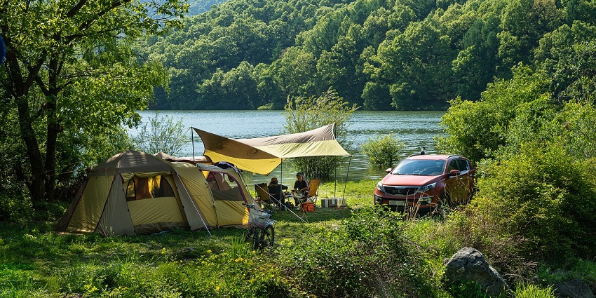 Tents on the shores of Pawna Lake with people standing and wandering around